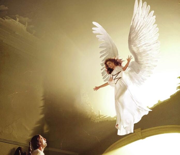 Poster for Angels in America featuring a radiant angel hovering above a man in a bed, bathed in golden light. The cast includes Al Pacino, Meryl Streep, and Emma Thompson.