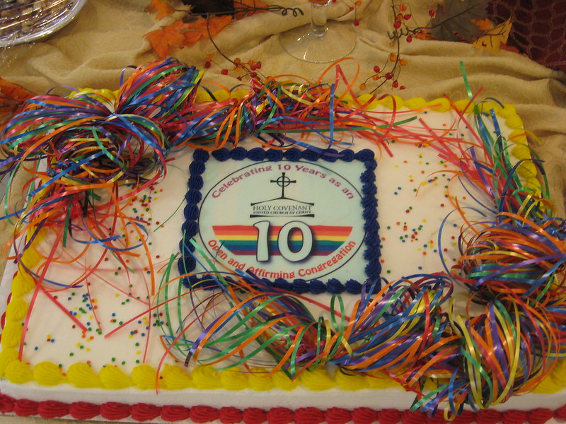 A celebratory cake with rainbow ribbons marking 10 years as an Open and Affirming congregation.
