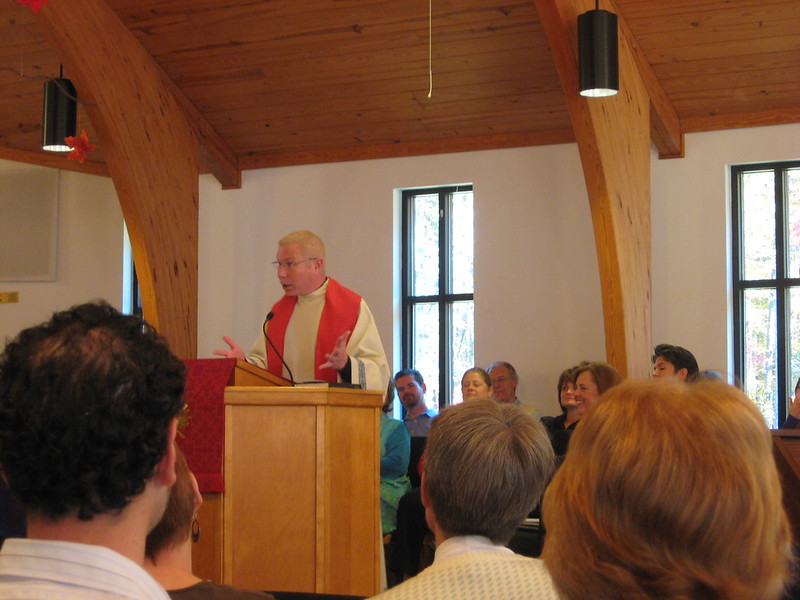 Rev. Troy Perry preaching from the pulpit in a red stole.