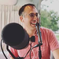 Smiling person speaking into a microphone during podcast recording.